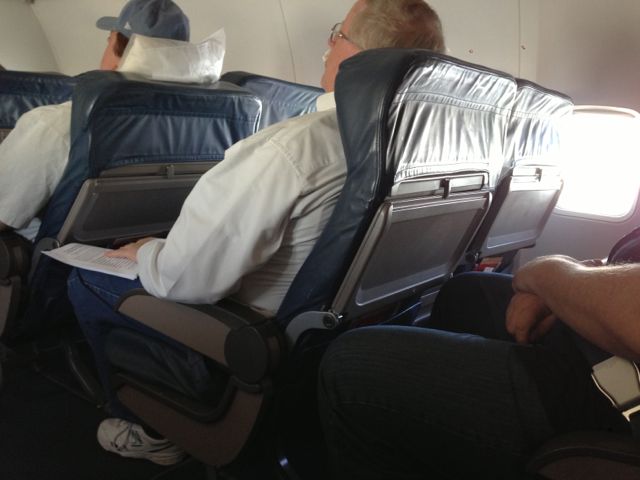 photo of three overweight middle aged men sitting in airplane first class