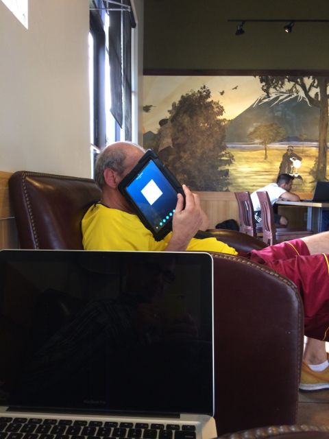Random photo of middle aged man talking using iPad at Starbucks