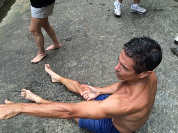 Shirtless, and soaked man sitting on rock