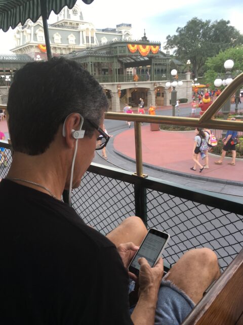 Man wearing head phones typing on phone at Disney