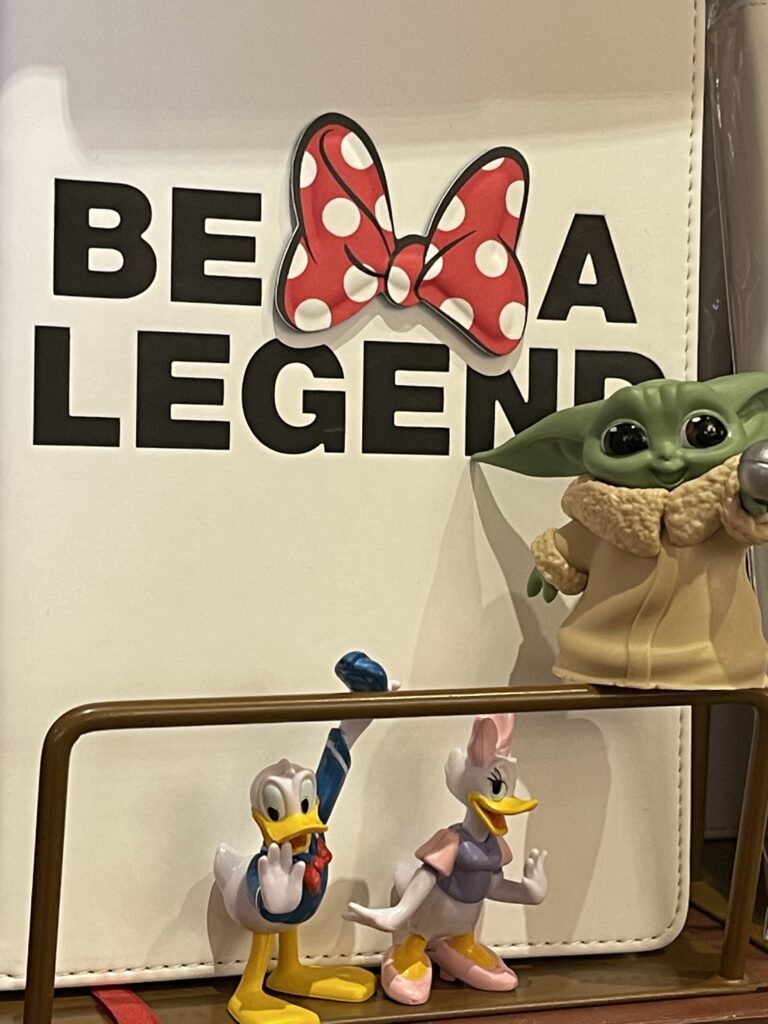 Small Disney toys in front of a logo be a legend