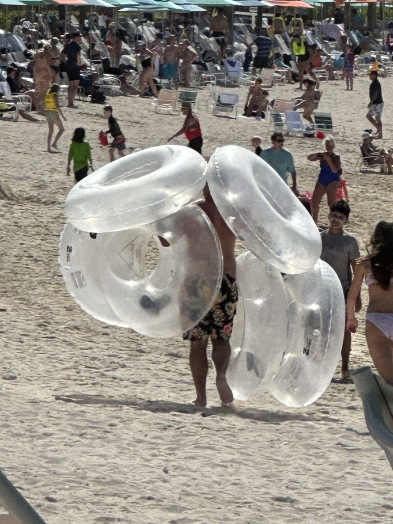 Man carrying six inner-tubes at beach