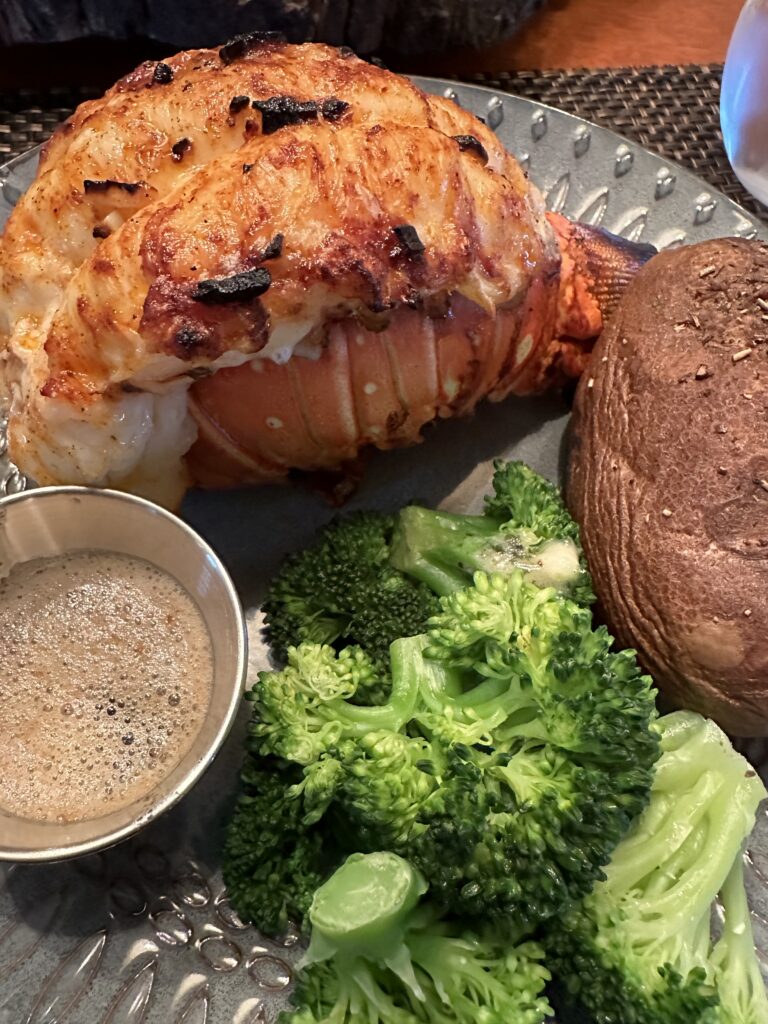Lobster tail baked potato, and broccoli on a plate